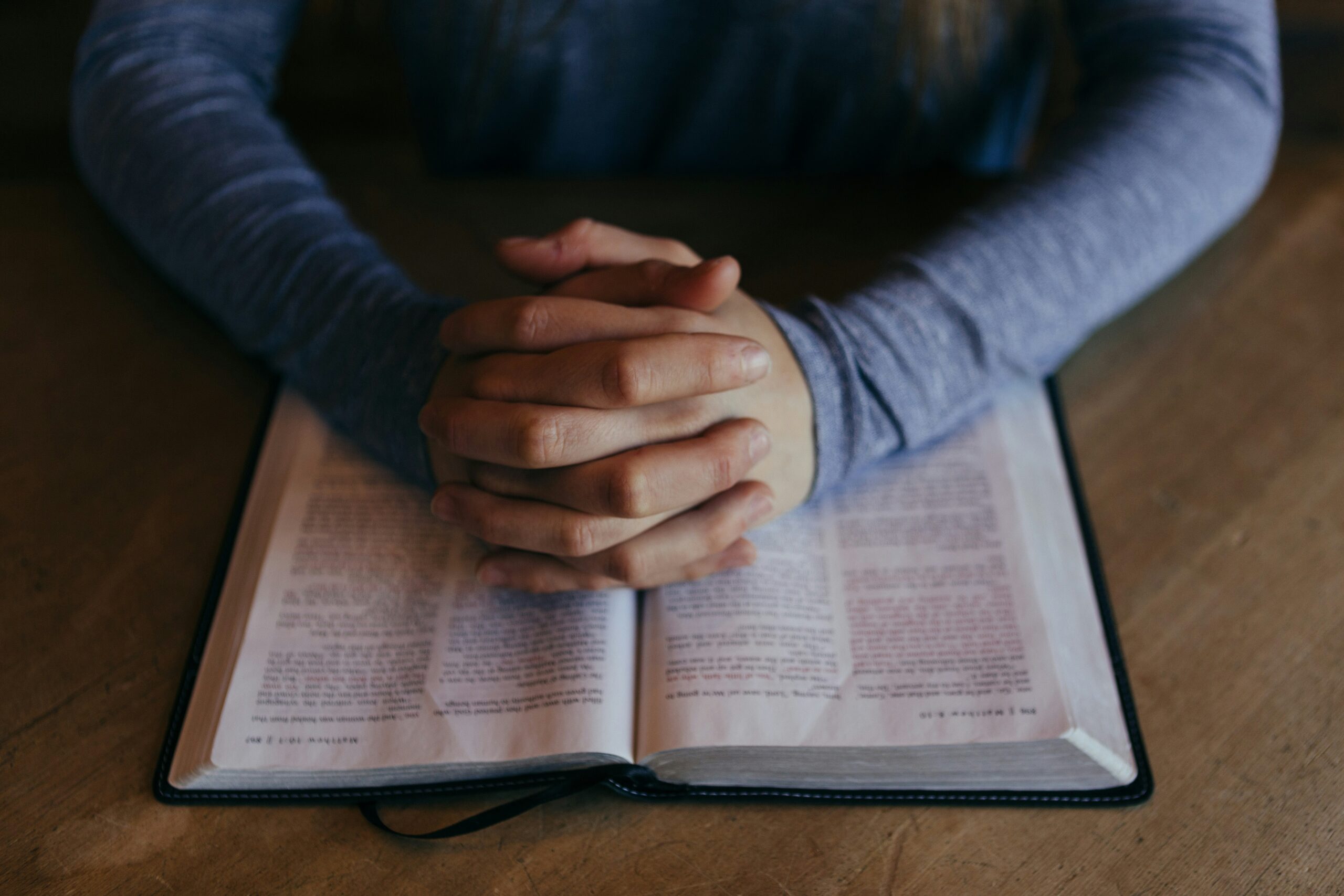 The Significance of Prayer in Christian Faith man holding his hands on open book