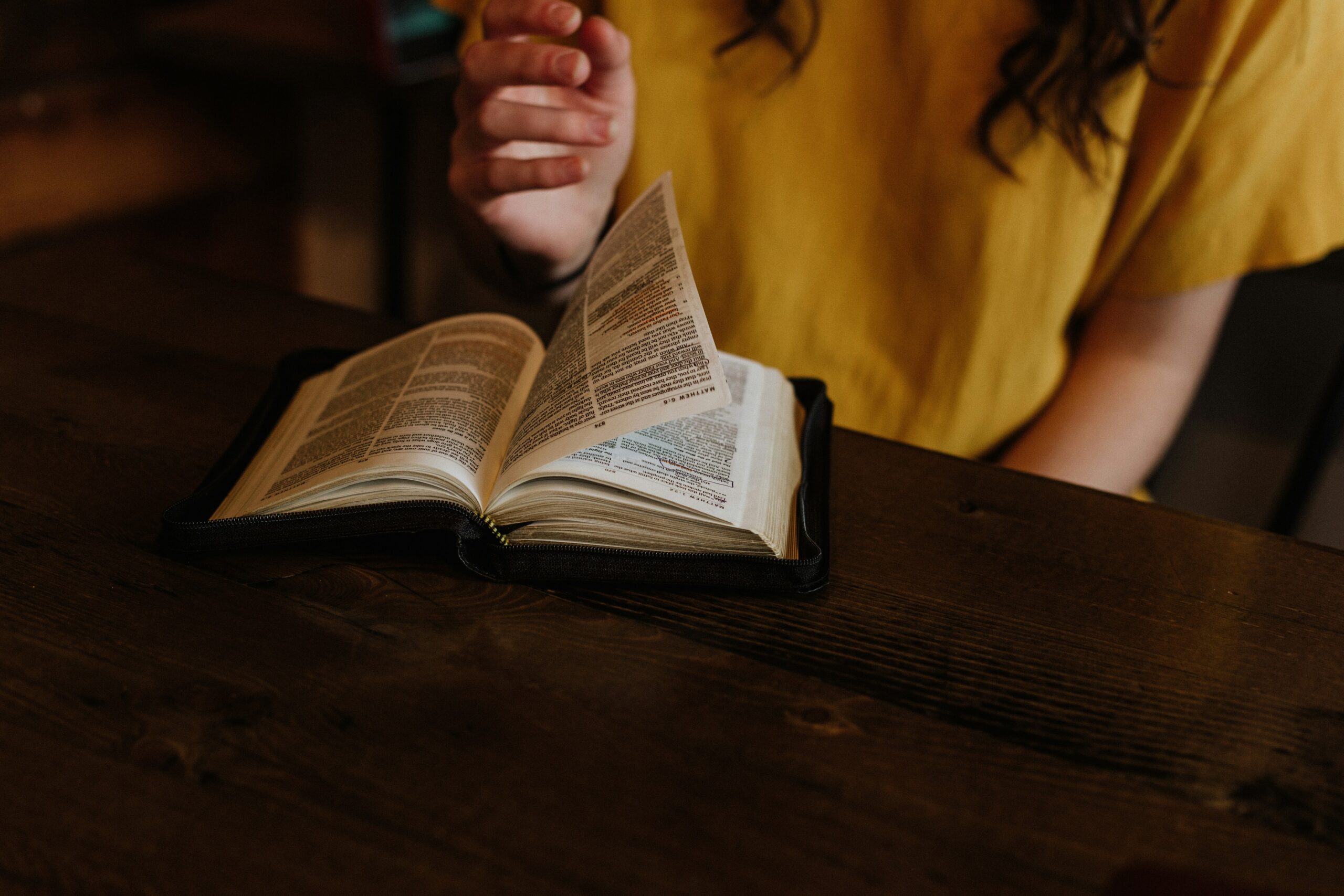 The Role of Women in the Bible: Examining Key Figures and Their Impact person reading Bible on top of brown wooden table