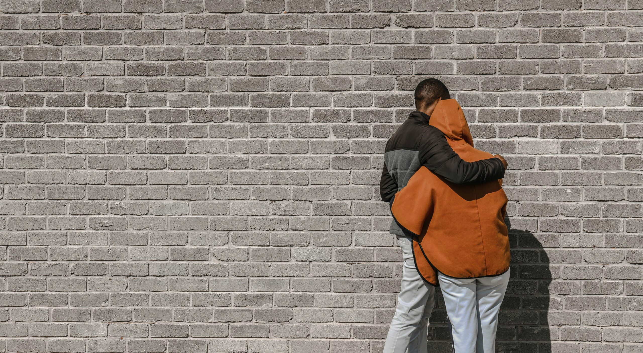 The Concept of Forgiveness in the Bible man in black and brown jacket and white pants standing beside brick wall